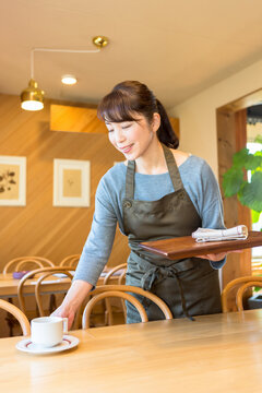 テーブルの片付けをする女性店員