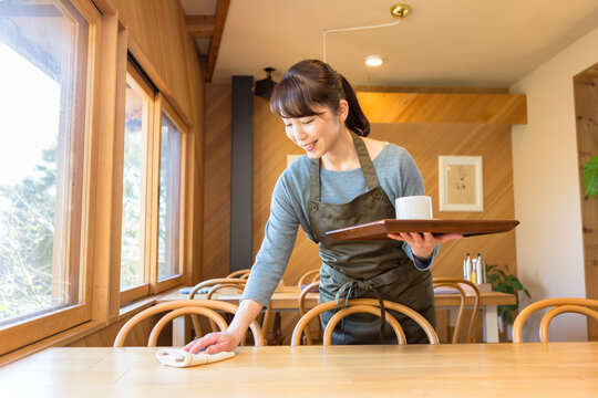 テーブルの片付けをする女性店員