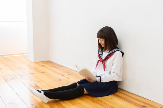 床に座って読書する女子中学生