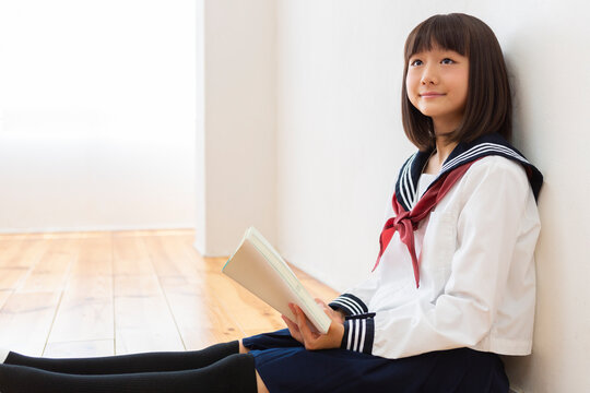 床に座って読書する女子中学生