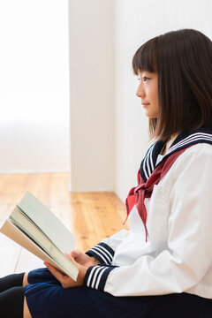 床に座って読書する女子中学生