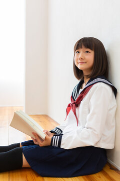 床に座って読書する女子中学生