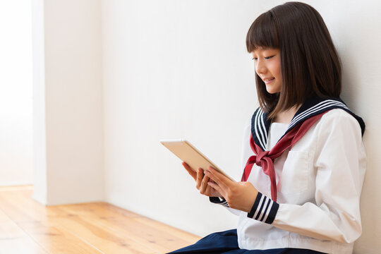 床に座って読書する女子中学生
