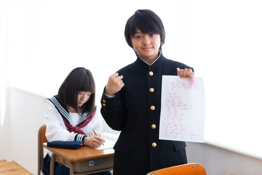 満点のテストを掲げる中学生