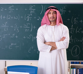 Arab teacher in front of chalkboard
