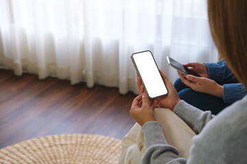 Mockup image of a couple woman holding and using a white mobile phone with blank desktop screen together