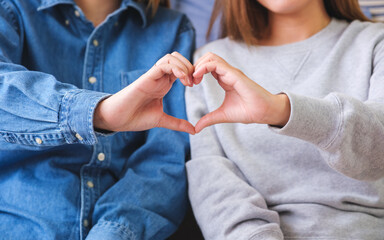 Closeup of a couple people making and showing heart hand sign together