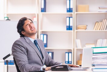 Young handsome employee in wheelchair at the office
