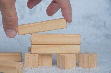Hand placing wooden block on top of other stacked wooden block with customizable space for text. Copy space.