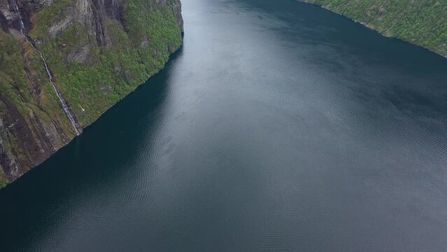 Geiranger aerial with slow tilt up from beautiful Unesco fjord to revealing seven sisters waterfall during spring - Norway