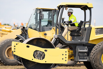 construction worker man drives heavy machinery for roadwork. man worker at construction machinery outdoor. A construction worker man used vibratory roller. busy worker man on construction equipment