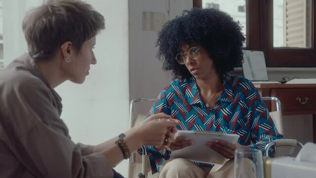 Young woman crying and complaining about depression to black female psychologist trying to support her and giving advice on therapy session