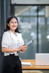 Fototapeta premium Young beautiful joyful happy woman employee officer business smiling while working, cute asian woman professional possibly accountant, happy interest manager bookkeeping firm law