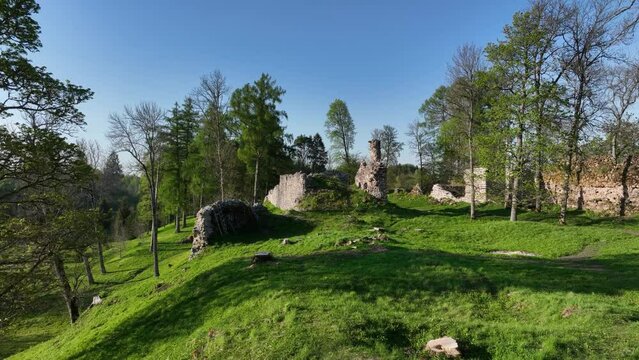 Drone flight among the ruins ruins of Helme Order Castle on a sunny evening. Estonia.