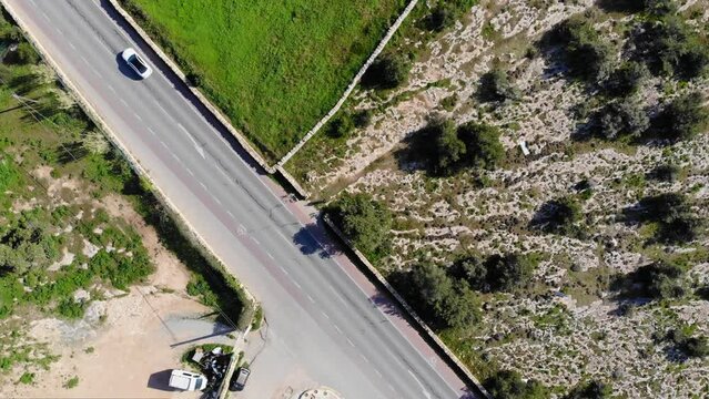 Drone footage facing down and turning, filming some cars passing by on the road.