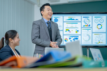 Office Conference Room Meeting Presentation: asian Businessman Talks, Uses Wall TV to Show Company Growth with Big Data Analysis, Graphs, Charts, Infographics. Multi-Ethnic e-Commerce Startup 