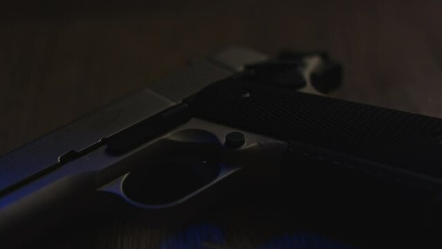 Close dolly out of a pistol with bullet casings lying on the floor with flashing police lights