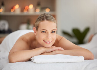 Portrait, relax and massage with a woman lying in spa for wellness treatment at a luxury resort on...