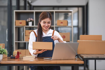 Startup happy Asian woman business owner works with a box at home office. prepare parcel delivery SME supply chain, procurement, package box to deliver to customers,