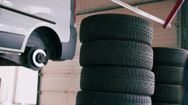 Warehouse of car tires on the background of a car without wheels on a lift at a car service