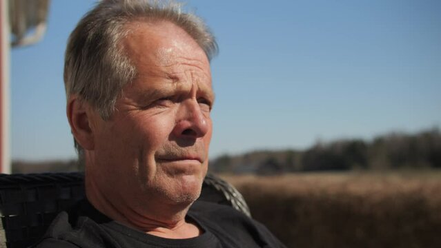Older middle-aged caucasian man sitting outside and thinking. Close up on face