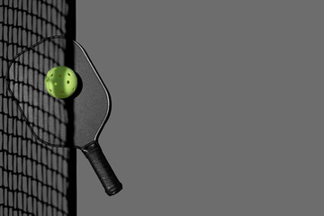 Flatlay of a pickleball paddle and ball on gray