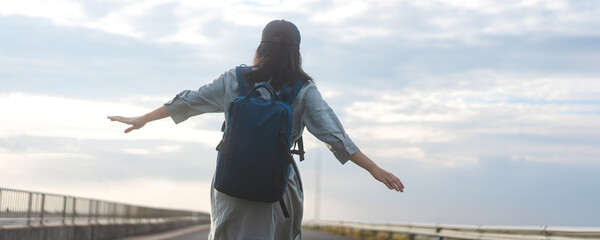 Rear view of woman traveler with backpack walking on road japanese mood with blue sky