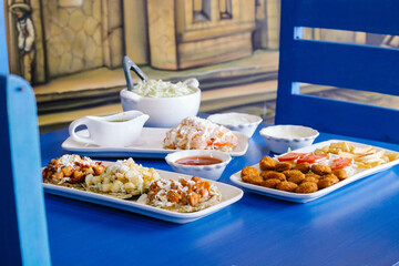 Mesa azul con plato de sopes, nugets de pollo y tostada de pata de puerco 