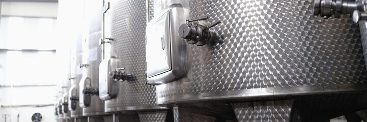Modern automated winery with lines of metal tanks. Interior view of modern brewery with stainless steel barrels. Shop with a brewery