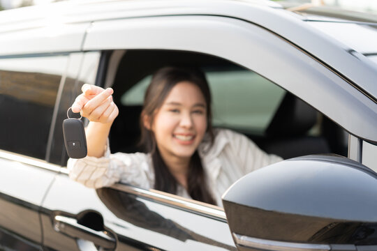 Dealership automobile, smile asian young woman, happy girl sitting in new car after purchase success, showing, holding auto remote key of vehicle, owner driver female buy gift for yourself at showroom