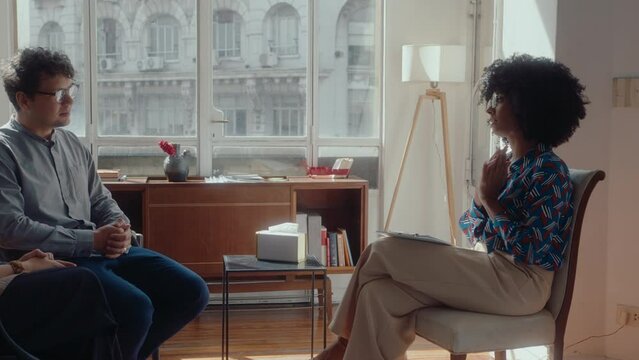 African-American female therapist speaking with family couple, helping to overcome relationship crisis, giving consultation at her office