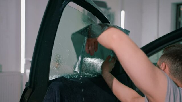 Male car service worker glue window tinting in luxury car detailing car repair the concept of love for cars and a protection