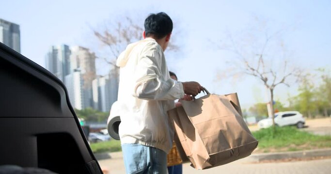 자동차를 주차하고 트렁크에서 쇼핑백을 꺼내는 아빠