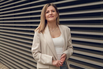 Confident businesswoman standing near striped wall