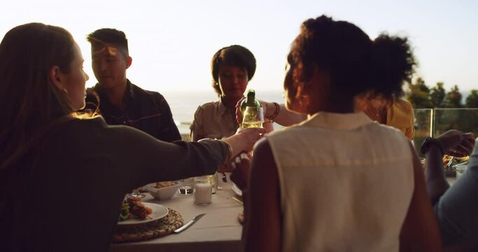 Group, friends and outdoor dinner at sunset and drinks, food and wine for people together for rooftop meal in nature. Women, men and diverse summer party, happy celebration or reunion of friendship