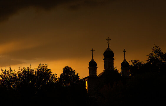 The silhouette of the domes of an Orthodox Christian church in Romania against the background of the red sky. Faith or religion concept photo