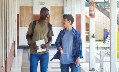 African boy meeting in the school hallway with his caucasian teenager schoolmate