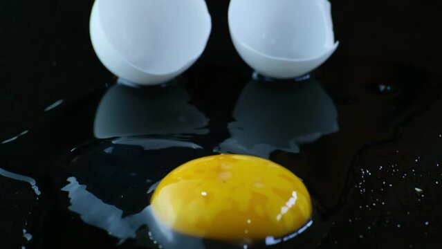 yolk and albumen to cleanly cracked egg shell on black background. slow movement dolly shott