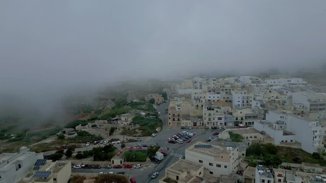 il-Bahrija Rabat, Malta picturesque village on a foggy day - pull back aerial reveal