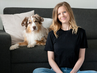 Frau mit Hund Australian Shepherd schwarzes T-Shirt Jeans Mockup Indoor Sofa Zuhause Kissen Couch