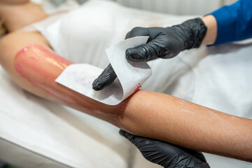 beautician doing cosmetological procedure epilation with hot sugar gel wax in hand