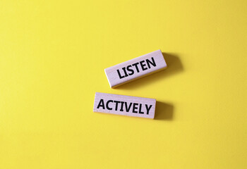 Listen actively symbol. Wooden blocks with words Listen actively. Beautiful yellow background. Business and Active listening concept. Copy space.