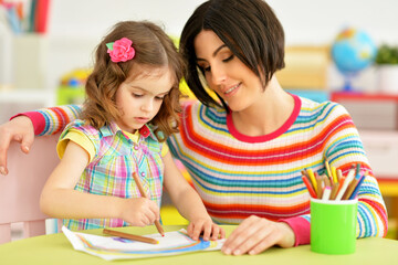 Fototapeta premium little cute girl with mother drawing at the table at home