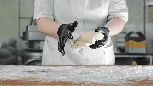 Women's hands in black gloves make the dough into a pasca shape. Kneading the dough and making the shape. Close up.