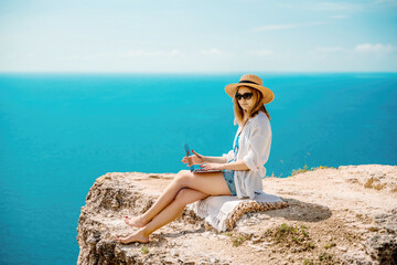 Freelance woman working on a laptop by the sea, typing away on the keyboard while enjoying the beautiful view, highlighting the idea of remote work.