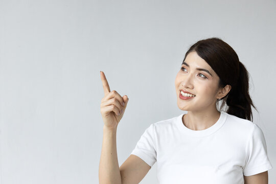 Happy smiling asian woman pointing up on isolated background