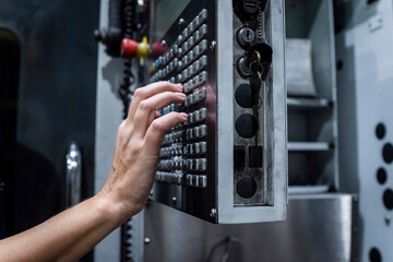 Hand of maintenance engineer operating CNC machine in modern factory