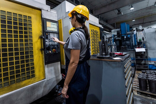 Maintenance engineer operating CNC Machine keypad in modern factory