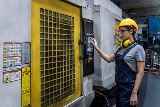 Engineer wearing hardhat operating CNC Machine in modern factory