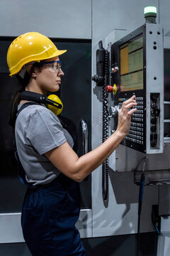 Maintenance engineer operating CNC machine keypad in factory